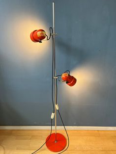 an orange lamp with two red lamps on it and a blue wall in the background