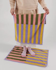 a person standing on top of a rug holding up a towel in front of them