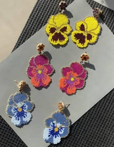 six pairs of flower earrings on top of a piece of paper