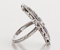 This unique one-of-a-kind antique conversion has been created out of the center of a 1920's filigree diamond and sapphire bracelet and a 1920's original etched wedding band. A fantastic Art Deco gift if we do say so ourselves!! Antique Ring - Antique Art Deco 18k White Gold Filigree Sapphire and Diamond Conversion RingArt Deco18k White GoldConversion3 Diamonds =.10ct8 French Cut Sapphires =.15ctRing Size Approximately 5.5 - 6. See photos of curve on center section. Ring measures 2.25" in length Antique White Gold Engraved Ring With Intricate Design, Antique Engraved White Gold Ring With Intricate Design, Ornate Platinum Jewelry, Ornate White Gold Engraved Rings, Antique Engraved White Gold Filigree Ring, Art Deco Engraved Filigree Ring For Formal Occasions, White Gold Oval Filigree Ring Engraved, Oval White Gold Filigree Ring Engraved, Engraved Oval Filigree Ring In White Gold