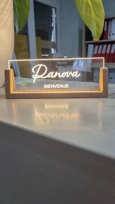 a glass plaque sitting on top of a wooden table next to a potted plant