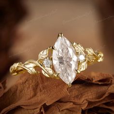 a gold ring with an oval cut diamond surrounded by leaves and diamonds on top of it