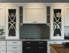 a kitchen with white cupboards and black counter tops, along with a wooden cutting board