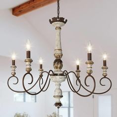 a chandelier hanging from the ceiling in a room with white walls and wooden beams