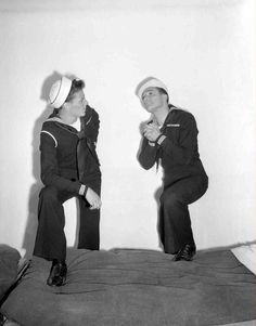 two men in sailor suits are sitting on a bed and one is holding his hands together