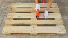 a person in white gloves is using a pair of scissors on a wooden pallet