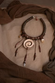 a necklace is laying on top of a piece of cloth with beads and other items around it