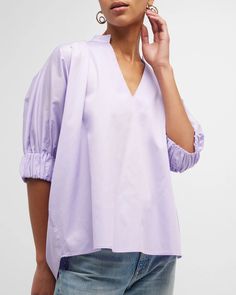 "Medina" Blouse is a this loose-fitting blouse that has become a best-seller. It features a V-neck collar and elbow-length sleeves with elasticized cuffs. Relaxed Fit. Material: 100% Cotton. Model 1 wears size 'S'. Model 2 wears size '1X'. Modern V-neck Blouse For Spring, Modern V-neck Blouse With Relaxed Fit, Modern V-neck Relaxed Fit Blouse, Modern V-neck Blouse For Daywear, Spring V-neck Smock Blouse, Spring Smock V-neck Blouse, V-neck Blouse With Pleated Sleeves, Oversized Blouse With Gathered Sleeves For Spring, Spring V-neck Tops With Cuffed Sleeves