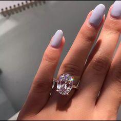 a woman's hand with a ring on it and a pink manicured nail polish