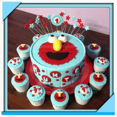 a birthday cake decorated with cupcakes and an elmo face