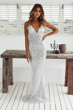 a woman standing in front of a table wearing a white dress with silver sequins