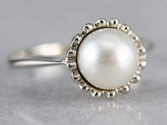 This pretty vintage piece is crafted of carefully detailed white gold that has just a perfect polish. Utterly simple, this vintage piece features a single, luscious pearl balanced by simple shoulders. Metal: 14K White Gold Gem: Pearl Gem Measurements: 7.2 mm, Round Ring Size: 4.50 SKU #: W794WK7K Each piece has been identified and graded by a Graduate Gemologist who has been certified by the Gemological Institute of America (GIA). We have four brick and mortar storefronts in Maine, Massachusetts White Gold Pearl Ring, Yellow Gold Sapphire Ring, Gold Pearl Ring, Pearl Rings, Ring White Gold, Brick And Mortar, Round Rings, June Birthstone, Solitaire Rings