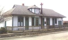 a small white building sitting on the side of a road next to a train track