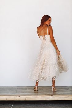 a woman in a white dress is standing on a wooden platform with her back to the camera