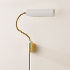 a wall lamp with a white shade on it and a black cord hanging from the side