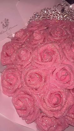 a bouquet of pink roses in a box with a tiara on the headpiece