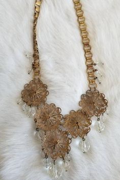 "This is a vintage 1920s-1930s statement necklace. The gold tone metalwork is very intricate and is in a round filigree design. There is one visible area of tarnish (pictured) from wear and age. The necklace has a unique chain and crystal tone details. All of the crystal tone gems are in excellent condition. Overall this necklace is in great condition. Measurements: Length: 9.5\" | Length of detail: 2.5\" Unless otherwise stated all vintage items are used and may have minor to moderate wear or d Antique Gold Vintage Necklace For Events, Vintage Filigree Jewelry For Vintage Events, Antique Gold Filigree Necklace For Formal Occasions, Vintage Brass Necklace For Formal Occasions, Vintage Brass Necklaces For Formal Occasions, Elegant Metal Necklace With Filigree Details, Elegant Metal Necklace With Filigree, Art Deco Gold Jewelry With Intricate Design, Ornate Necklace With Intricate Design For Vintage Events