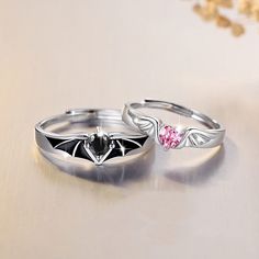 two rings with bats on them sitting next to each other and one has a pink diamond in the middle