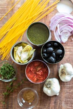 the ingredients for an italian pasta dish are arranged in small tins on a wooden surface