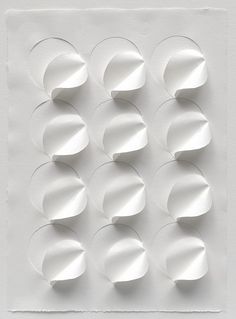 white paper circles are arranged in the shape of an abstract pattern on a white surface