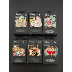 six disney pin badges are shown on a black surface