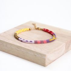 This handwoven multi-color beaded bracelet is a vibrant accessory that adds a pop of color to any outfit. Crafted with meticulous care, it features a colorful box chain design, making it perfect for summer vibes. Each bead is delicately strung together to create a unique and eye-catching pattern, making this bracelet a stylish addition to your jewelry collection. Perfect for adding a playful touch to your look, this seed bead bracelet is sure to become a staple accessory for any fashion-forward Multicolor Braided Bead Bangle Bracelet, Multicolor Braided Bracelet Bangle, Multicolor Braided Bangle Bracelet, Multicolor Beaded Friendship Bracelets, Multicolor Beaded Braided Bracelets, Multicolor Hand-strung Braided Bangle Bracelet, Multicolor Friendship Bracelets With Colorful Beads, Adjustable Multicolor Braided Bracelet With Letter Beads, Multicolor Tiny Beads Braided Bracelets For Friendship