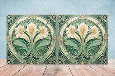 two decorative panels with flowers on them sitting on a wooden table in front of a blue wall