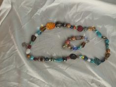 a multicolored beaded necklace with charms on it sitting on a white sheet