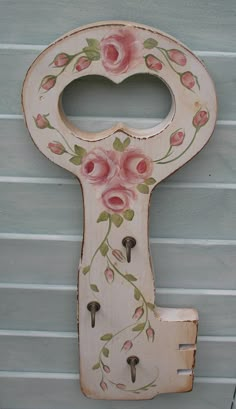 an old wooden key with flowers painted on the front and back of it, hanging from a wall