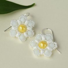 Our pearl flower earrings feature a cheerful, yellow pearl surrounded by over 150 white beads hand-woven into an intricate flower pattern.  The beaded flower dangles from sterling silver filled earrings that add a touch of sparkle.  The nature inspired jewelry will effortlessly enhance your style and add a pop of color to your summer wardrobe.  Embrace the beauty of nature with our lightweight, handmade earrings.  FIT:  The beaded flower is ¾ of an inch in diameter and the drop is roughly 1 inch Handmade Silver Flower Pearl Earrings, White Pearl Beaded Drop Earrings, Sterling Silver Flower Earrings With Pearl Drop, White Pearl Drop Beaded Earrings, Elegant White Flower Shaped Beaded Earrings, Handmade Flower Pearl Earrings, Handmade Flower-shaped Pearl Earrings, White Pearl Drop Flower Earrings, White Pearl Earrings In Flower Shape