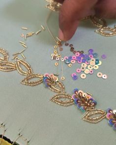 someone is working on some beading with gold and purple beads in the middle of it