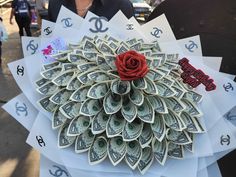 a bouquet made out of dollar bills with a red rose on the center and letters that spell love