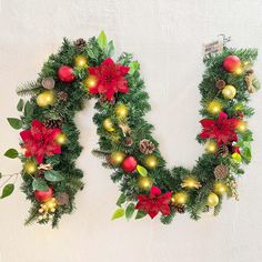 a christmas wreath with poinsettis and pine cones hanging on the wall next to a potted plant