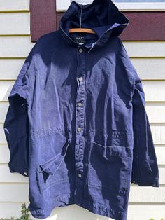 1980's dark indigo cotton canvas hooded parka. Brand is Peace Blues. Made in the USA. Buttons down front. Beautiful patina and definitely wearable  but does have some condition issues: missing drawstring for waist, missing second from bottom button, front pocket is ripped at the seam and some light discoloration on front and back. Please refer to pictures. Sold as is. Tagged Small but definitely not accurate. Was meant to be quite oversized. Measured flat:  Shoulder: 24" Chest: 24" Length: 35" Sleeve: 25" Best fit: Unisex Large to XL. Please measure against yourself for best fit. Oversized Cotton Utility Parka, Casual Cotton Parka With Adjustable Hood, Blue Cotton Hooded Jacket With Pockets, Casual Cotton Parka With Double-lined Hood, Navy Cotton Hooded Jacket For Fall, Cotton Dark Wash Outerwear For Outdoor, Dark Wash Cotton Outerwear For Outdoor, Utility Cotton Hooded Jacket With Double-lined Hood, Washed Cotton Hooded Outerwear