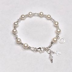 This lovely First Communion bracelet features real pearls and Swarovski crystals. This bracelet is sure to be the perfect gift! Each First Communion bracelet is made with sterling silver elements and includes a sterling silver cross and heart charm. Make it extra special by personalizing it with a sterling silver hand-stamped initial charm and birthstone. Makes an ideal gift for Baptism, First Communion, Confirmation, Easter, Flower Girls, Maid-of-Honor, Bridesmaids, Mother-of-the-Bride, Godmoth Pearl Charm Bracelet For First Communion, Pearl Bracelet For First Communion, Adjustable Pearl Bracelet For First Communion, Adjustable Pearl Bracelet With Charm For First Communion, Adjustable Pearl Charm Bracelet For First Communion, White Pearl Bracelet For First Communion, Pearl White Bracelet For First Communion, Adjustable Pearl Bracelets For Baptism, Pearl White Pearl Bracelet For First Communion