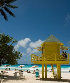 a yellow lifeguard tower sitting on top of a sandy beach