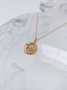 This Gold Sun & Moon necklace is elegant and simple, and hangs from a delicate chain.  The sun and moon represent different things in different cultures but the one thing that is common in all of them is their polarity. The sun symbolizes firmness, strength and power while the moon represents calmness, beauty, nurturing. It looks great on its own or layered with other necklaces, and is the perfect everyday accessory. Item Details: Pendant: H: 21 mm L: 21 mm W: 1 mm Necklace clasp: lobster clasp. Celestial Charm Necklace With Moon Phase Pendant, Celestial Moon Phase Charm Necklace With Round Pendant, Celestial Sun And Moon Charm Necklaces, Celestial Sun And Moon Charm Necklace, Dainty Sun And Moon Charm Necklace, Moon Shaped Celestial Necklace With Sun And Moon Design, Celestial Moon Necklace With Sun And Moon Design, Celestial Moon-shaped Necklace With Sun And Moon Design, Dainty Sun And Moon Round Pendant Necklace