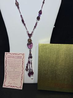 "Sunya Currie Purple And Clear Venetian Glass Beaded Necklace. The necklace has a gold tone metal tag that says Sunya Currie. There is 1 cupcake bead. It has no clasp it just slips over your head. The necklace measures: 36\" The tassel hangs an extra 6 \" longer It comes with the original gift box, velvet bag and provenance.. (Jewelry # 4276) USA Seller!! Estate sale find. We do not Clean or Polish our Estate Jewelry we will leave that to you. We also have Jewelry, Hallmark Ornaments, Dept 56, Vintage Glassware and many other items. We will combine shipping for multiple items if possible. Features: * no clasp Size: Womens 36\" Condition: Pre-Owned Like New" Gold Beaded Tassel Necklace Gift, Spiritual Beaded Necklaces With Dangling Beads As Gift, Glass Beaded Necklaces With Dangling Beads As Gifts, Costume Jewelry Long Beaded Necklace As Gift, Beaded Dangle Long Necklace For Gift, Beaded Dangle Long Necklace As A Gift, Costume Jewelry Long Beaded Chain Necklace Gift, Adjustable Tassel Necklace With Dangling Beads For Gift, Beaded Chain Long Necklace As Costume Jewelry Gift