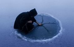 a person kneeling down in the middle of a frozen lake with their hands on the ground