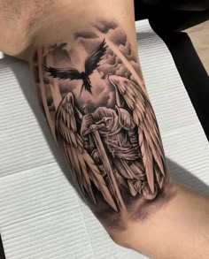 a man's arm with an angel and cross tattoo on the left side of his leg