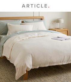 a bed with white sheets and blue pillows