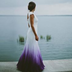 a woman in a white and purple dress looking out at the water