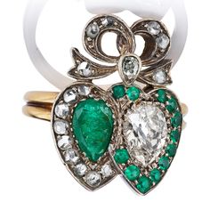 Rare Victorian Antique Emerald and Diamond Ring The Kinsey ring is an authentic antique emerald and diamond ring from the Victorian Era circa 1880. The ring features a Pear Cut Emerald and a Pear Cut Diamond, each of approximately 0.70 carats. An additional 16 Rose Cut diamonds and emeralds create a double-heart shaped halo and bow around and above the stones. The stones are set in a 14kt gold and silver setting. The ring is currently size 6 and can be resized! Why We Love It An incredibly rare Vintage Emerald Ring With Diamond For May Birthstone, Vintage Diamond Emerald Ring For May Birthstone, Antique Emerald Cut Emerald Ring With Center Stone, Antique Emerald Ring For Wedding, Vintage Emerald Ring With Brilliant Cut For Gift, Vintage Diamond Ring With Center Stone For May Birthstone, Vintage Green Emerald Ring With Single Cut Diamonds, Vintage Emerald Ring With Brilliant Cut For May Birthstone, Vintage Emerald Ring For Anniversary