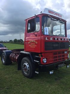 a red truck parked on top of a lush green field