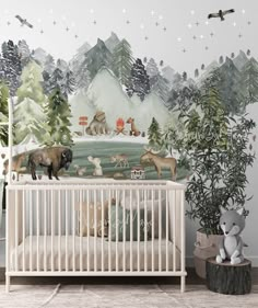 a baby crib in front of a wall mural with animals and trees on it