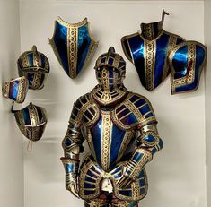 an elaborately designed blue and gold suit on display in a white room with other items