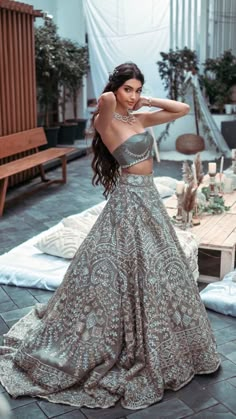 a woman in a silver and gold dress posing for the camera with her hand on her hip