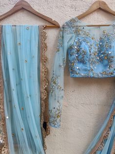 This fresh powder blue raw silk lehenga has thread and sequin butti embroidery all over.  It is paired with a mirror, sequins, beads and thread embroidered tulle blouse. The outfit is completed with an embroidered net dupatta. Unstitched Embellished Blue Sharara, Light Blue Semi-stitched Lehenga With Resham Embroidery, Light Blue Resham Embroidery Sets For Navratri, Fitted Blue Pre-draped Saree With Intricate Embroidery, Light Blue Sets With Intricate Embroidery, Festive Light Blue Dupatta With Intricate Embroidery, Light Blue Sets With Sheer Dupatta For Diwali, Embellished Blue Sets For Reception, Light Blue Resham Embroidery Anarkali Set For Festivals