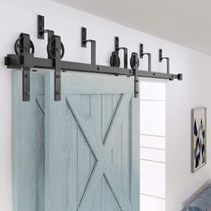 a blue barn door with black hardware on the top and bottom, in front of a white wall