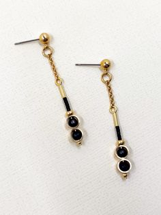 These earrings are dainty and minimalistic but detailed! Thick, straight cut, golden brass rings encircle each semi precious stone of matte black onyx, complimentary tiny, matte black glass seed beads sit above.  The shiny warm, golden brass contrasts beautifully with the deep black stone.  The simplicity and geometric shapes create a contemporary design.  A solid brass ball stud with stainless steel earring post sits at the top.  Approximate measurements- 5.5 cms long 0.75 cm wide All Set Theory jewellery comes with care instructions and a polishing pad to keep your jewels looking fabulous and shiny! ✨ Black Dainty Metal Jewelry, Dainty Black Metal Jewelry, Minimalist Matte Gold Metal Jewelry, Minimalist Gold Plated Linear Earrings With Adjustable Chain, Minimalist Metal Linear Earrings With Adjustable Chain, Minimalist Black Linear Earrings For Gifts, Elegant Black Earrings With Adjustable Chain, Single Black Brass Earring, Minimalist Black Linear Earrings As Gift